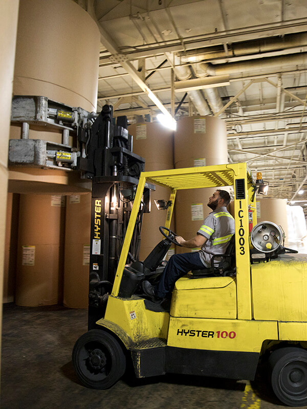 forklift driver moving lare rolls of industrial size paper